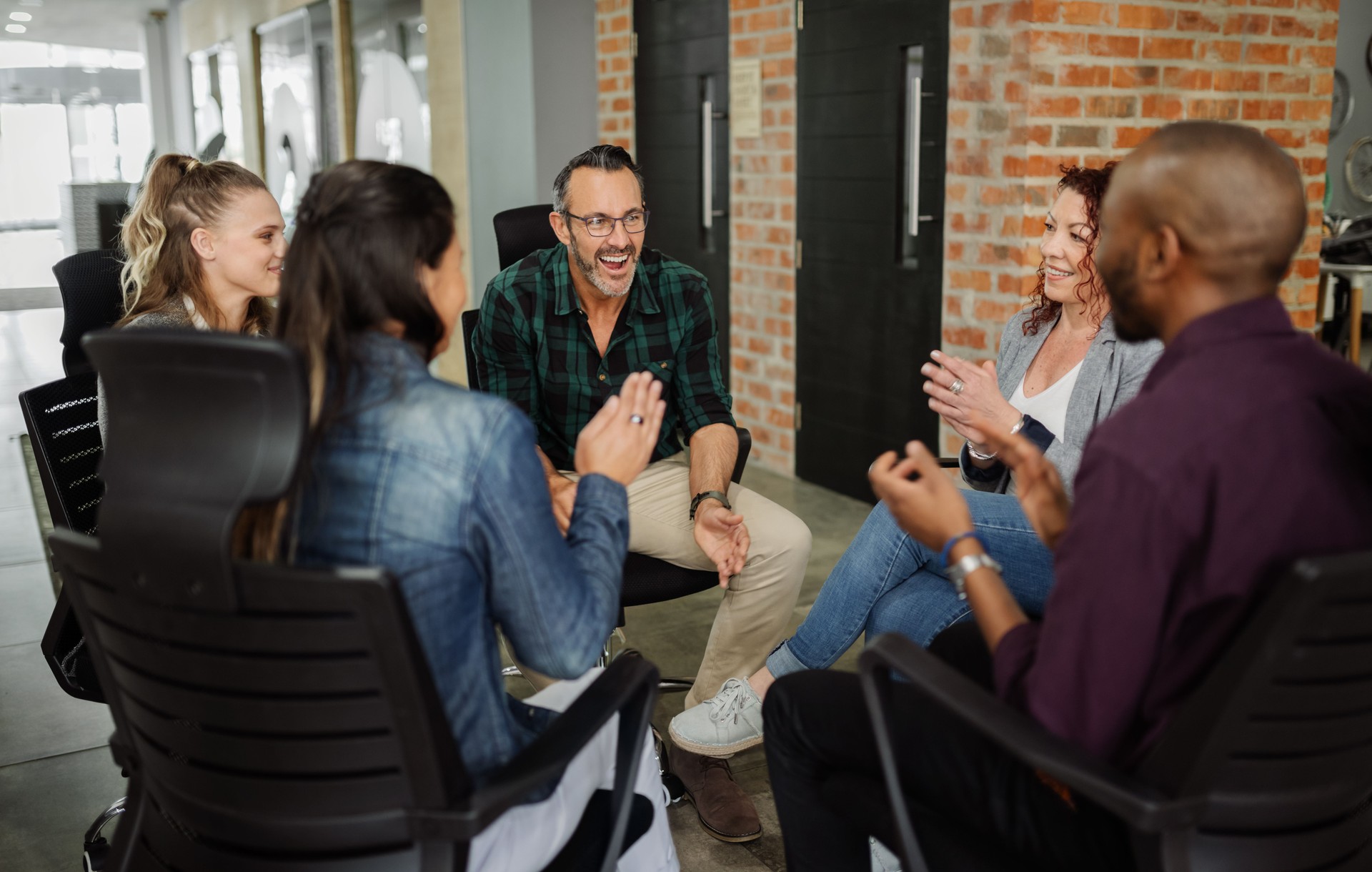 Diverse group of business people sitting in circle. Handsome man talking with coworkers in a team building session.